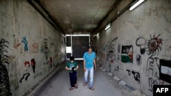 Omar Hajajla, warga Palestina berjalan dengan putranya melalui terowongan yang menghubungkan rumah mereka di Yerusalem ke al-Walajah, desa mereka di Tepi Barat, 30 Mei 2019. (Foto: AFP)