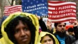 FILE - People hold signs before marching to Trump Tower in a protest organized by the New York Immigration Coalition against President-elect Donald Trump in New York, Dec. 18, 2016.