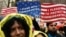 FILE - People hold signs before marching to Trump Tower in a protest organized by the New York Immigration Coalition against President-elect Donald Trump in New York, Dec. 18, 2016.
