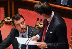 Italian Premier Giuseppe Conte, right, looks at Deputy-Premier Matteo Salvini who addresses the Senate in Rome, Aug. 20, 2019.