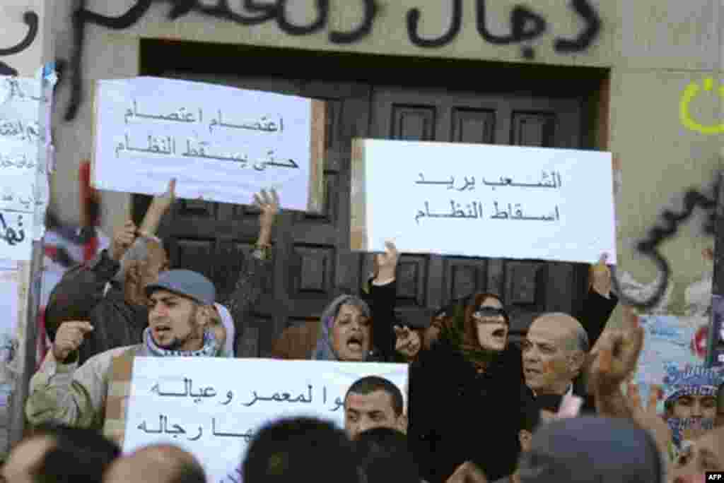 This photograph, obtained by The Associated Press outside Libya and taken by an individual not employed by AP, shows people chanting and holding signs during recent days' unrest in Benghazi, Libya. Placards in Arabic read at top left "Strike, strike unti