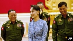 Myanmar's NLD party leader Aung San Suu Kyi smiles with army members during the handover ceremony of outgoing President Thein Sein and new President Htin Kyaw at the presidential palace in Naypyitaw, March 30, 2016. 