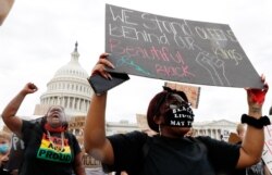 Dominique Bryant, 23, left, and Nastajia Walker, 21, right join demonstrators as they gather to protest the death of George Floyd, June 3, 2020, outside the U.S. Capitol in Washington.