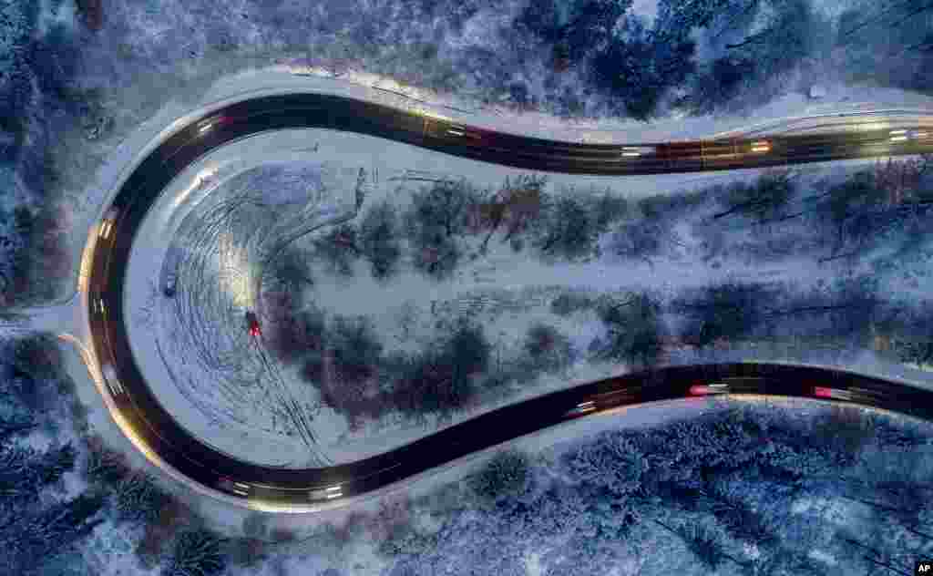 Cars drive through curve in a forest of the Taunus region near Frankfurt, Germany, after snow falls during the night.