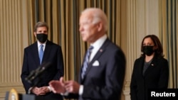 El presidente Joe Biden, en primer plano, se dirige a los periodistas, en presencia de la vicepresidenta Kamala Harris y del enviado presidencial especial para el Cambio Climático de la Casa Blanca, John Kerry, en la Casa Blanca, el 27 de enero de 2021.