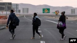 Venezolanos caminan por la carretera camino a Iquique, luego de cruzar desde Bolivia, en Colchane, Chile, el 18 de febrero de 2021.