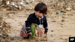 A Syrian refugee girl sits on mud at a refugee camp, in the eastern Lebanese Town of Al-Faour near the border with Syria, Lebanon, Tuesday, Dec. 2, 2014. 