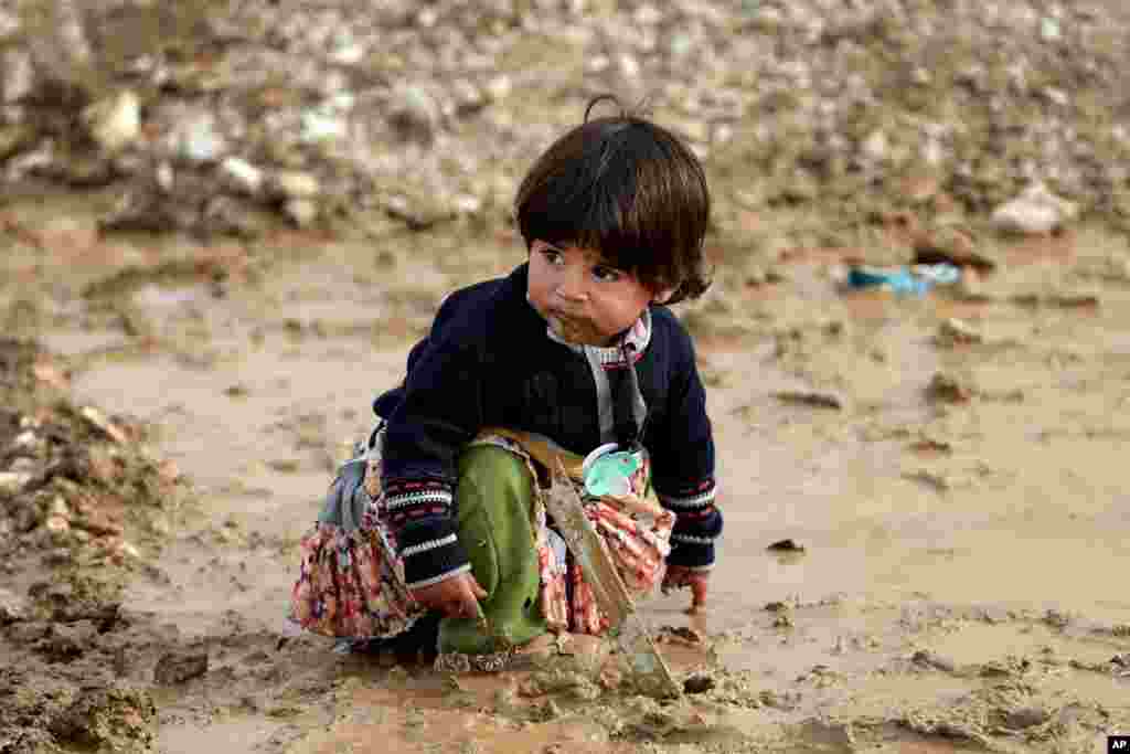 A Syrian refugee girl sits on mud at a refugee camp in the eastern Lebanese Town of Al-Faour near the border with Syria, Lebanon.