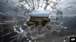 FILE - The city of Mekele is seen through a bullet hole in a stairway window of the Ayder Referral Hospital, in the Tigray region of northern Ethiopia, May 6, 2021. Ethiopian military airstrikes hit the capital of the country's Tigray region on Oct. 18, 2021