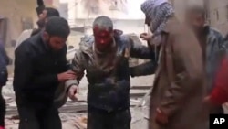 In this frame grab from video released Jan. 1, 2018 by the Syrian Civil Defense group, known as the White Helmets, Syrians help an injured man on a stretcher after an airstrike hit the Damascus suburb of Masraba, Syria. 