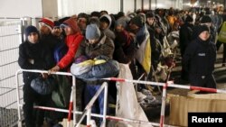 FILE - Migrants queue on a street to enter the compound outside the Berlin Office of Health and Social Affairs (LAGESO) for their registration process in Berlin, Germany, Dec. 9, 2015.