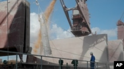 FILE - A worker watches corn being loaded into a grain ship in the port of Rosario, about 300 kilometers (190 miles) north of Buenos Aires, Argentina, April 5, 2006. Wednesday and explosion at the shipping hub killed one employee and injured eight others.
