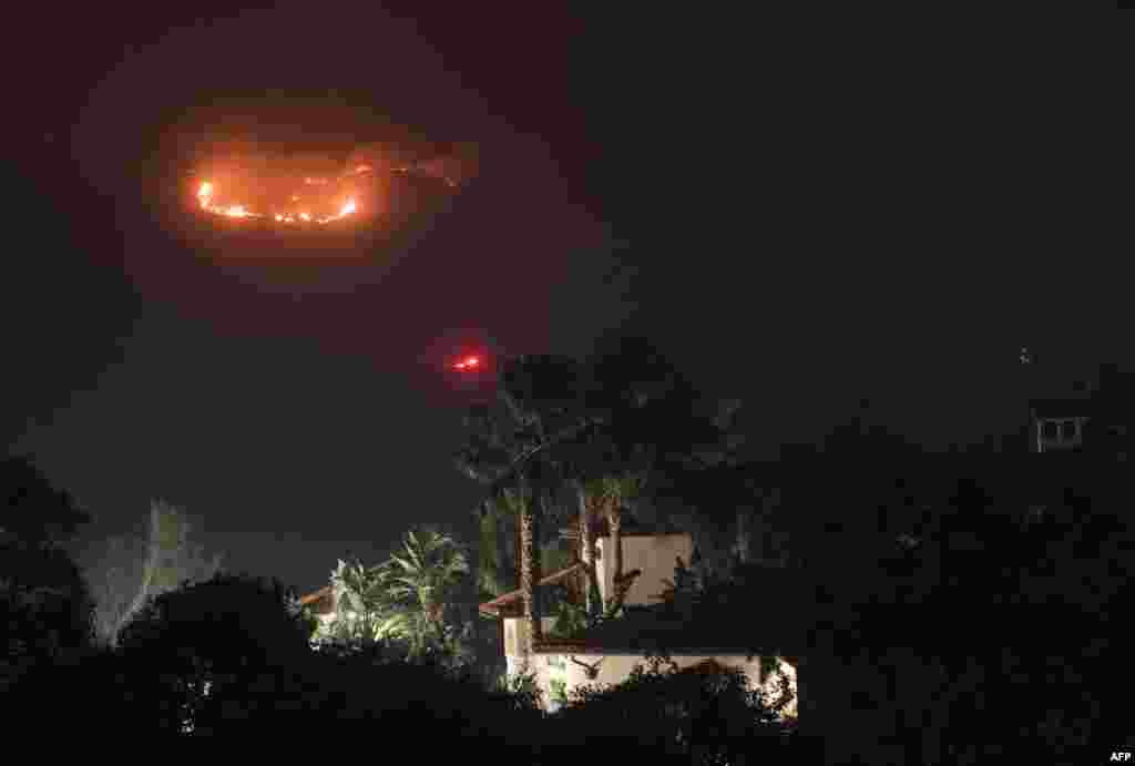 Fire burns in the hills behind a home at the Thomas Fire in Montecito, California, Dec. 16, 2017.