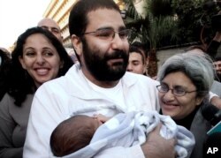 FILE - Egyptian prominent blogger Alaa Abdel-Fattah, center, hugs his recently born son, Khaled, his mother, Laila Soueif, right, and his sister, Ahdaf Soueif, left, after his release, in Cairo, Egypt.