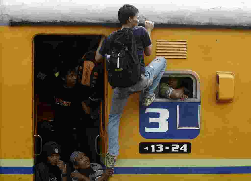 Seorang penumpang yang tidak dapat tempat di dalam kereta nekat naik dengan berpegangan pada pintu dan jendela kereta tujuan Jawa Timur yang berangkat dari Stasiun Senen, Jakarta.