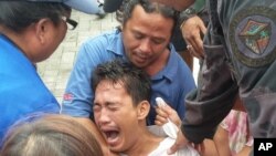 Police and rescuers comfort a crying passenger after he was brought ashore from a capsized passenger ferry July 2, 2015, in Ormoc city, central Philippines. 