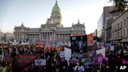 In this June 3, 2017 photo, Maira Maidana, bottom right, holds a banner with pictures of herself during a march organized by the movement "Ni Una Menos," or Not One Less, in Buenos Aires, Argentina. (AP Photo/Natacha Pisarenko)