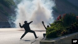 Opponents to Venezuela's President Nicolas Maduro throw stones at soldiers loyal to the president inside La Carlota airbase in Caracas, Venezuela, Tuesday, April 30, 2019. 