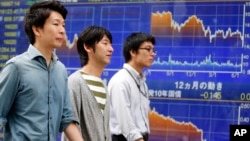 People walk past an electronic stock indicator of a securities firm in Tokyo, June 22, 2016.