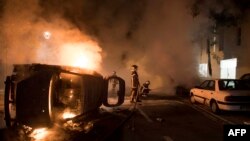 Firefighters work to put out a fire near a burning car in the Malakoff neighborhood of Nantes, France, July 4, 2018. 