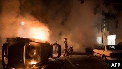 Firefighters work to put out a fire near a burning car in the Malakoff neighborhood of Nantes, France, July 4, 2018. 