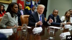 FILE - President Donald Trump, center, is flanked by White House staffer Omarosa Manigault Newman, left, and then-Housing and Urban Development Secretary-designate Ben Carson as he speaks during a meeting on African American History Month in the Roosevelt Room of the White House in Washington, Feb. 1, 2017. Manigault Newman released a new book "Unhinged," about her time in the White House.