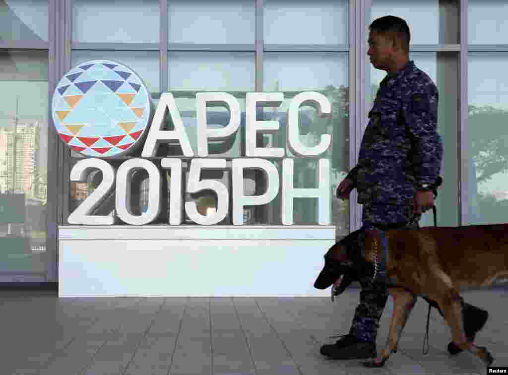Seorang tentara melewati logo APEC dengan anjing pelacak di pusat media KTT APEC di Manila, Filipina (17/11). (Reuters/Edgar Su)