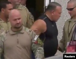 Cesar Sayoc, who was arrested during an investigation into a series of parcel bombs, is escorted from an FBI facility in Miramar, Florida, Oct. 26, 2018 in a still image from video.