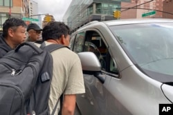 FILE - Wang Gang, 36, front, a Chinese immigrant, and others talk to a motorist as they try to find work in construction or another trade in New York, May 3, 2024. U.S. authorities are stepping up efforts to deport undocumented Chinese nationals.