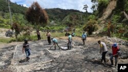 Warga dan polisi membersihkan puing-puing di lokasi dugaan serangan oleh kelompok militan di Desa Lemban Tongoa, Sulawesi Tengah, Selasa, 1 Desember 2020.(Foto: AP)