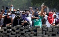 FILE - Protesters yell from behind the roadblock they erected as they face off with security forces near the University Politecnica de Nicaragua in Managua, Nicaragua, April 21, 2018.