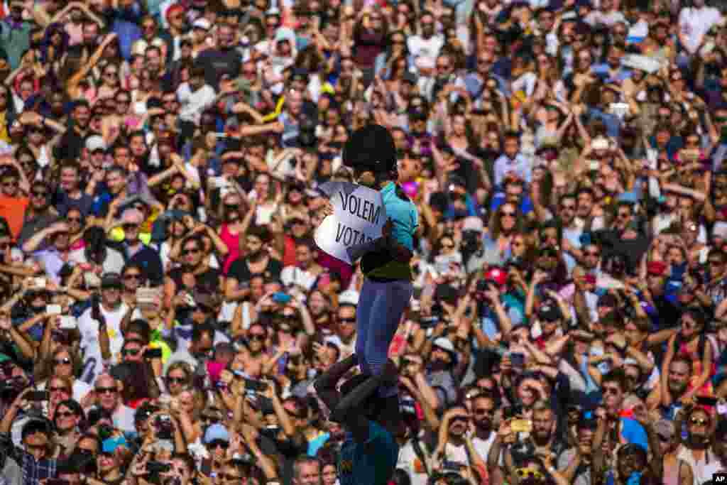 A member of a castelle holds a placard reading in Catalan &quot;We want to vote&quot;, as she crowned the human tower in Sant Jaume square in Barcelona, Spain.