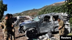 Lebanese army soldiers inspect a damaged vehicle marked with "Press" at the site of an Israeli strike on guesthouses used by media, Lebanon's health ministry and local media reported, in Hasbaya in southern Lebanon, Oct. 25, 2024.