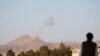 也门萨那附近一处山间军营受到空袭后，一名男子遥望从军营升起的浓烟。（2015年3月30日）