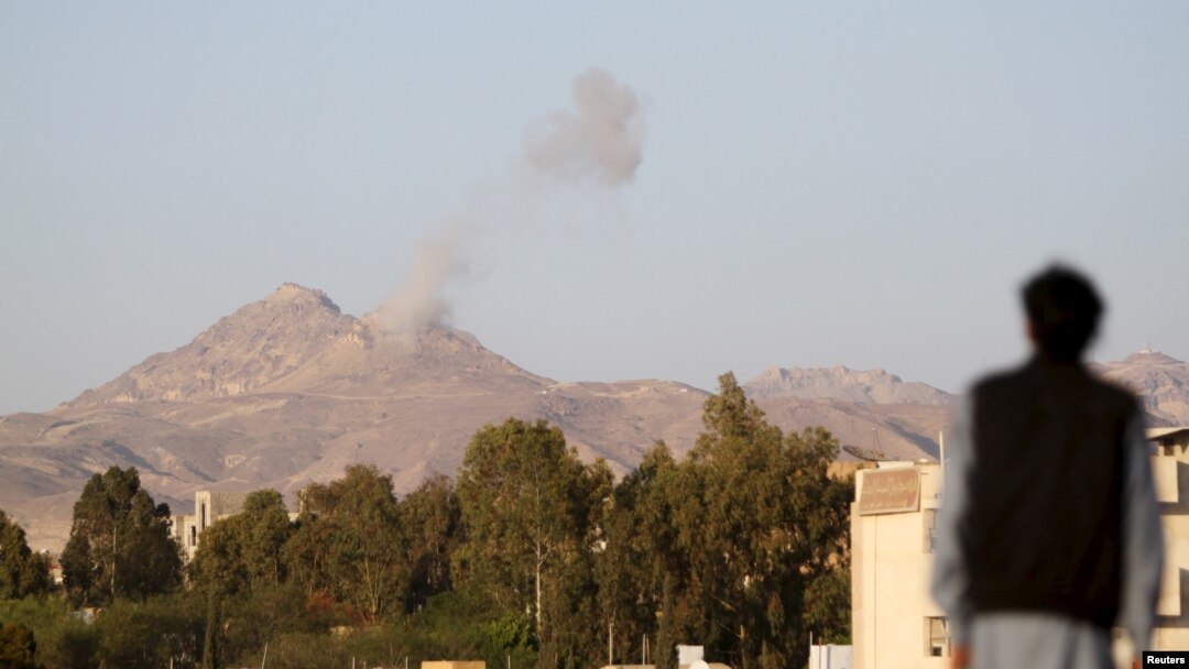 A man looks on as smoke billows from military barracks in the Jabal al-Jumaima mountain following an airstrike near Sana'a, Yemen, March 30, 2015. 