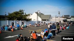 Orang-orang mengantri untuk pergi ke pantai Long Branch pada hari pertama pantai New Jersey dibuka kembali menjelang akhir pekan Hari Pahlawan setelah wabah corona, di Long Branch, New Jersey. (Foto: Reuters)