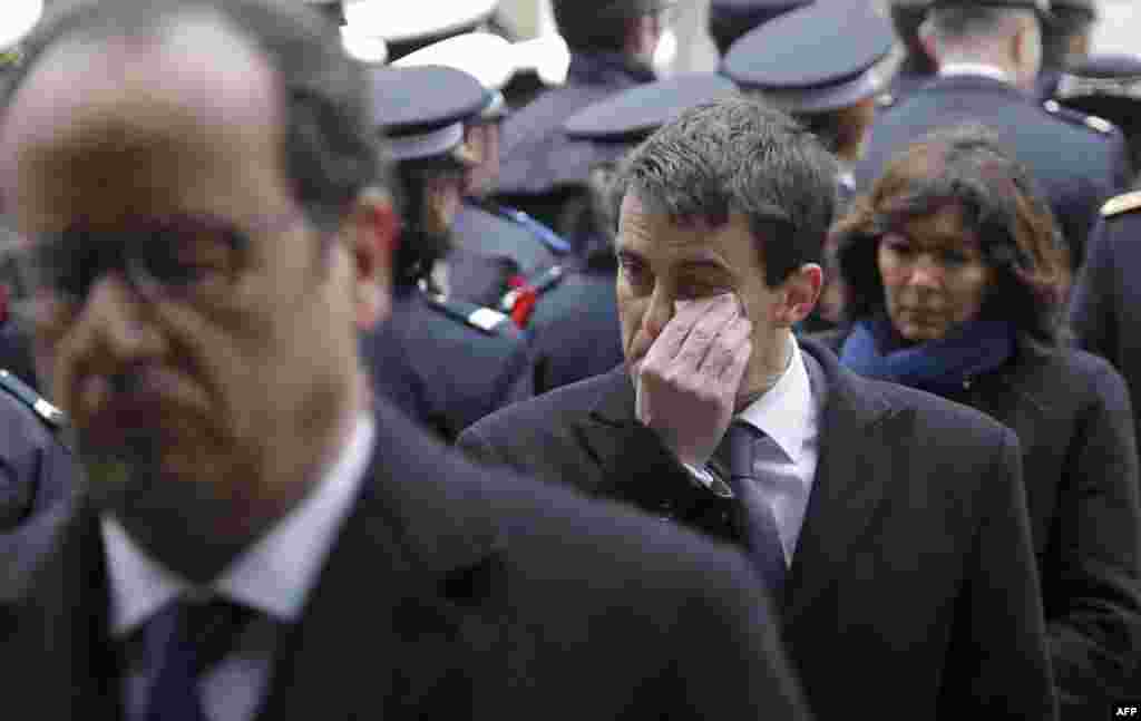 Prime Minister Manuel Valls, center, dries his tears, next to French President Francois Hollande, left, and Paris Mayor Anne Hidalgo during a ceremony to pay tribute to the three police officers killed in the attacks, in Paris, France, Jan. 13, 2015. 
