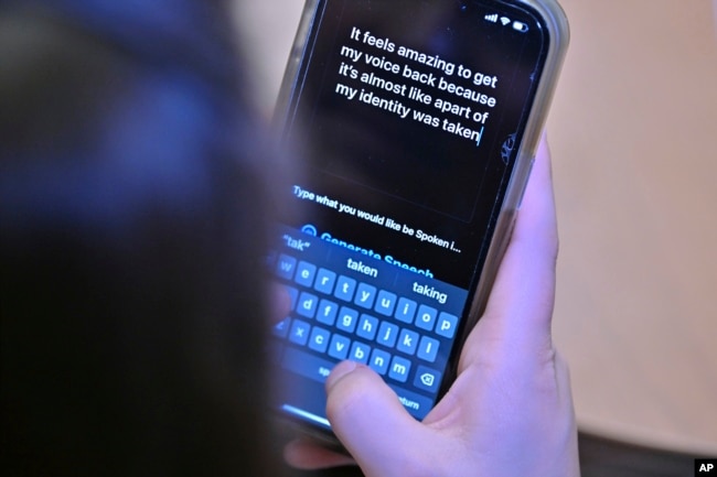 Alexis Bogan types a response to a reporter's question with an app which approximates her lost voice, Thursday, March 11, 2024, at Rhode Island Hospital in Providence, R.I. (AP Photo/Josh Reynolds)