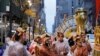 FILE - A woman in a flower costume marches in front of the Wiggle Worm balloon during last year's Macy's Thanksgiving Day Parade, November 28, 2019, in New York.