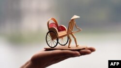 A craftman poses with a bamboo miniature sculpture in Hanoi, Vietnam.