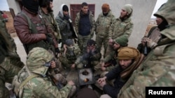 Rebel fighters warm by a fire on the outskirts of the northern Syrian town of al-Bab, Syria, Jan. 14, 2017.