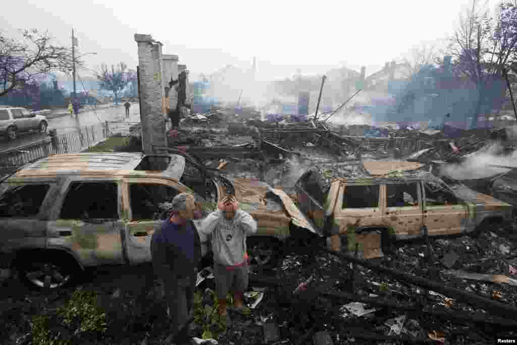 Residents look over the remains of burned homes in the Rockaways section of New York, October 30, 2012. 