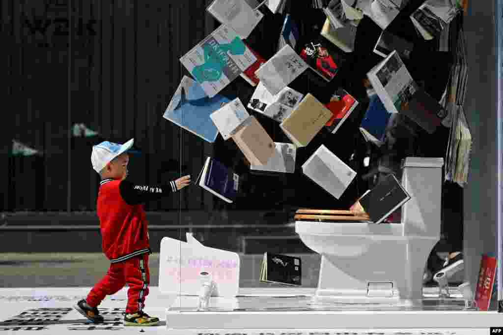 A child walks toward to a promotional booth set up outside a shopping mall on World Book Day in Beijing, April 23, 2021.