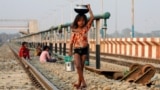 A girl carries water in a pot and a bucket on the outskirts of Agartala, India.