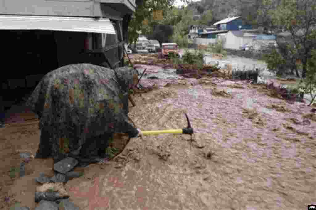 Jason Foulds shovels mud and debris in a flooded area of Silverado Canyon, Calif., Wednesday, Dec. 22, 2010. Storm runoff and mud has prompted the evacuation of about 30 people in the area. After days of relentless rain, Southern California on Wednesday w