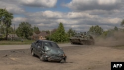 Ukrajinska samohodna haubica 2S1 Gvozdika prolazi pored oštećenog automobila u oblasti Vovčansk, u regionu Harkova, 12. maja 2024.
