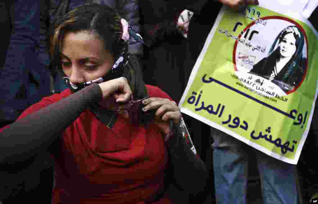 An Egyptian woman cuts her hair during a demonstration in Tahrir Square, Cairo, Egypt. Women cut their hair to protest against the Islamist-oriented constitution on Tuesday, Dec. 25.