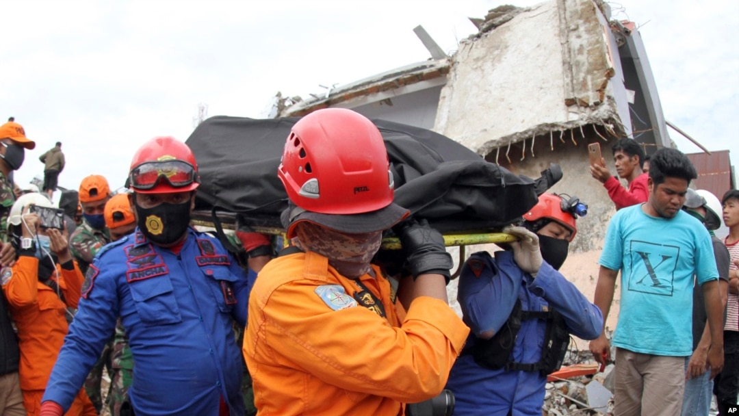 Rescuers carry the body of an earthquake victim retrieved from the ruin of a building damaged by an earthquake in Mamuju, West Sulawesi, Indonesia, Jan. 16, 2021.