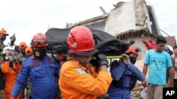 Rescuers carry the body of an earthquake victim retrieved from the ruin of a building damaged by an earthquake in Mamuju, West Sulawesi, Indonesia, Jan. 16, 2021.