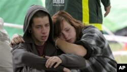 Kent Manning, 15, and Libby Manning, 18, wait for news of their mother who is trapped in the CTV building in Christchurch, New Zealand, after the city was hit by a 6.3 earthquake on Tuesday, February 23, 2011